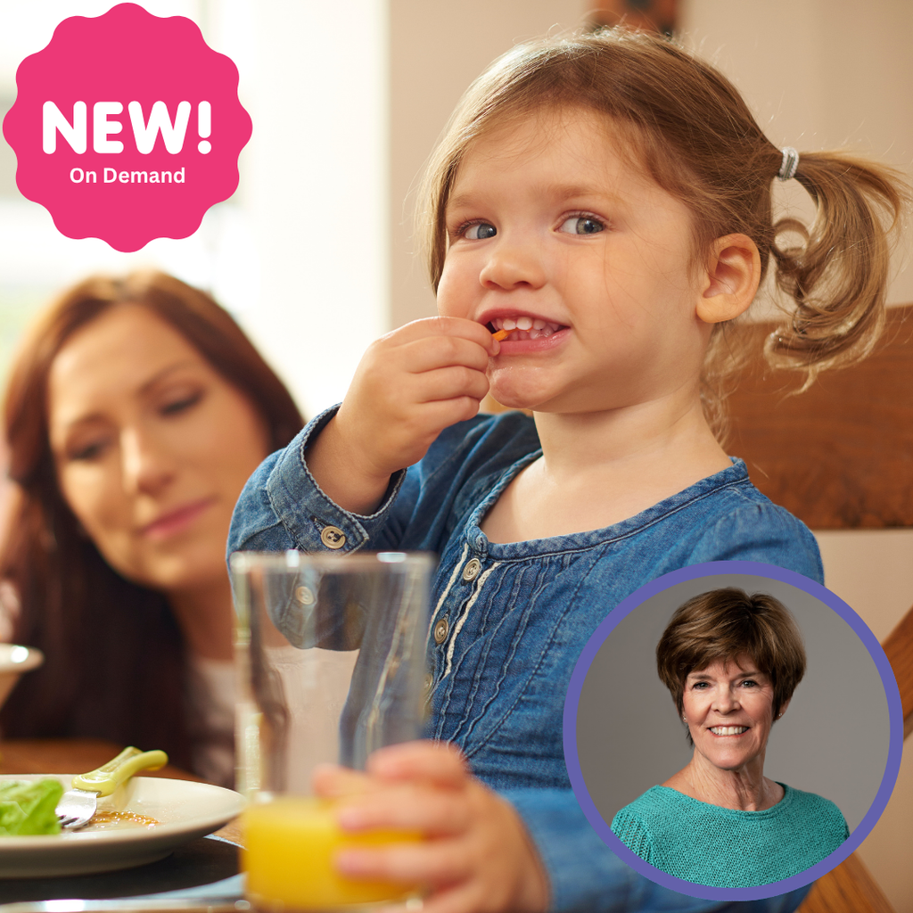 A young girl in a blue shirt eats while sitting at a table, with an adult woman in the background and drinks nearby.